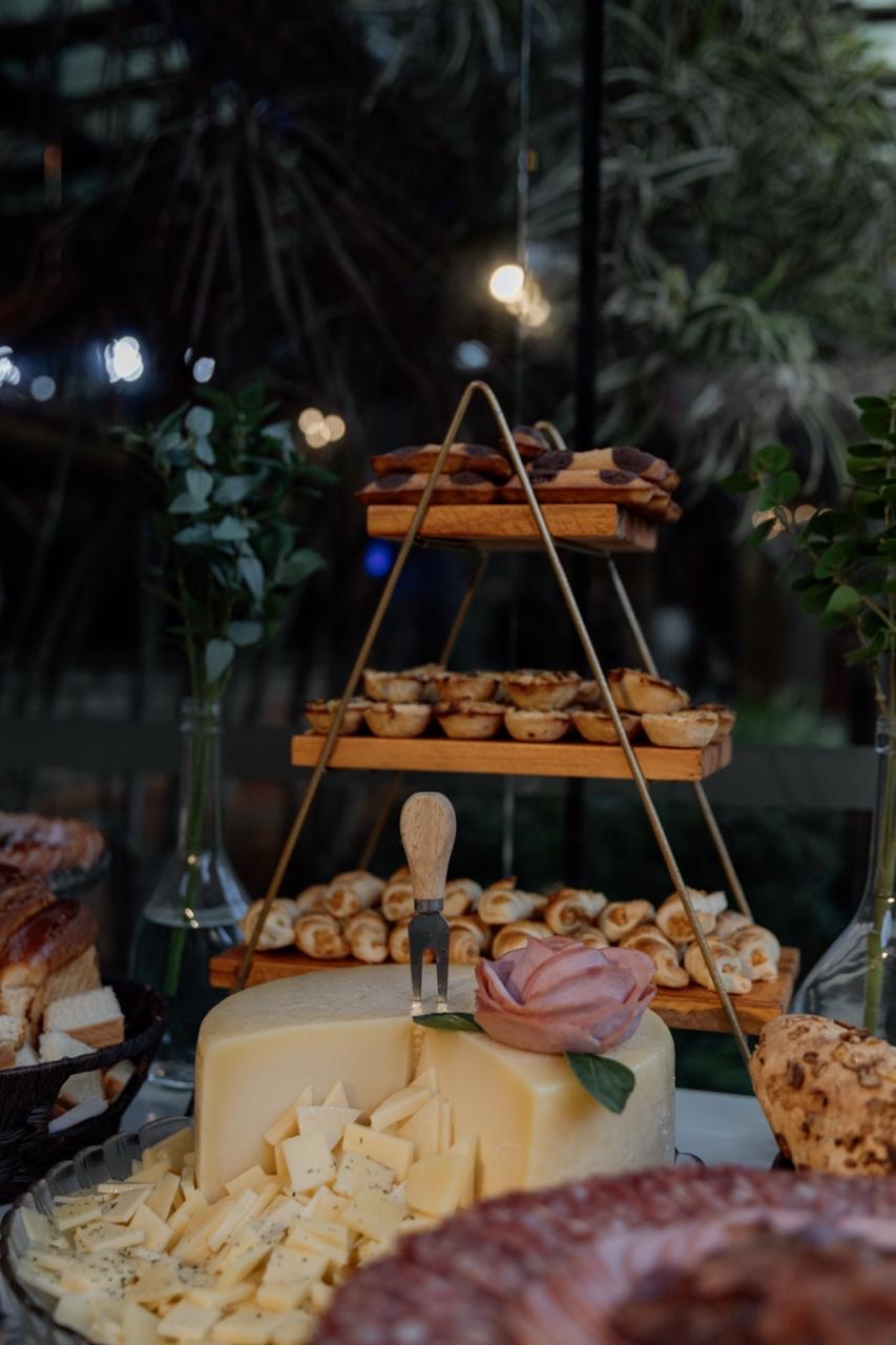Torre de antepastos com queijos, mini-empanadas e canapés sob luzes pendentes