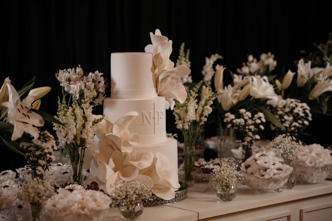 Bolo de casamento com monograma personalizado e arranjos florais