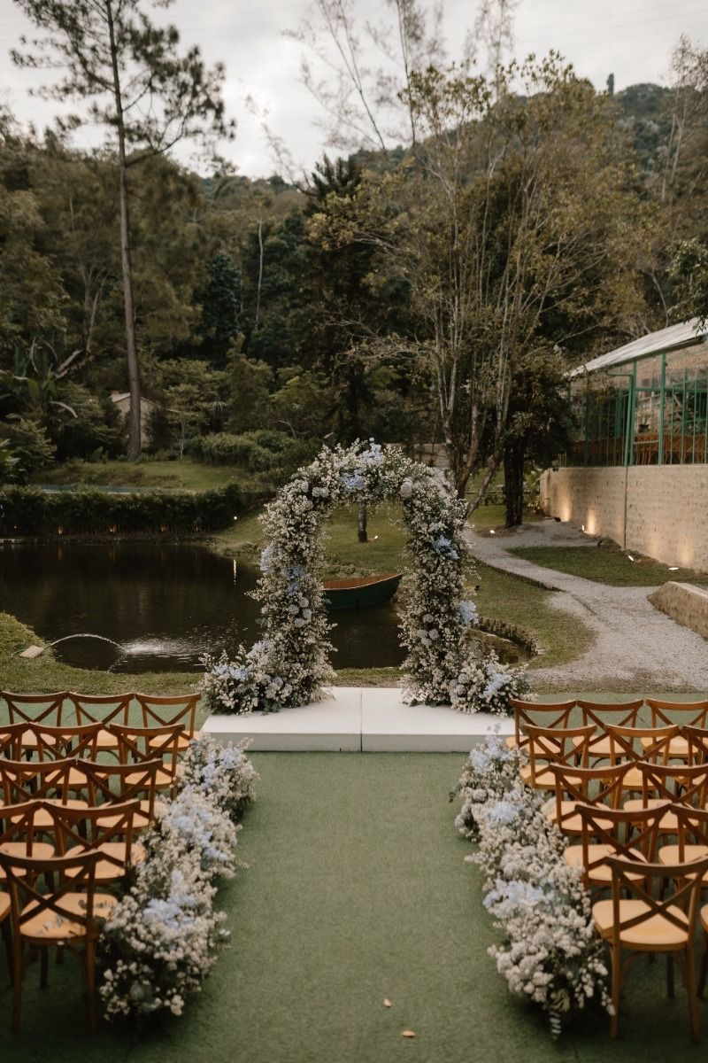 Cerimônia ao ar livre com arco floral, cadeiras alinhadas e luz natural dourada