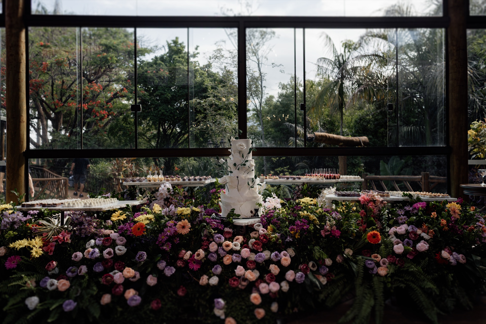 Mesa de doces com bolo, flores e doces finos sob luz suave