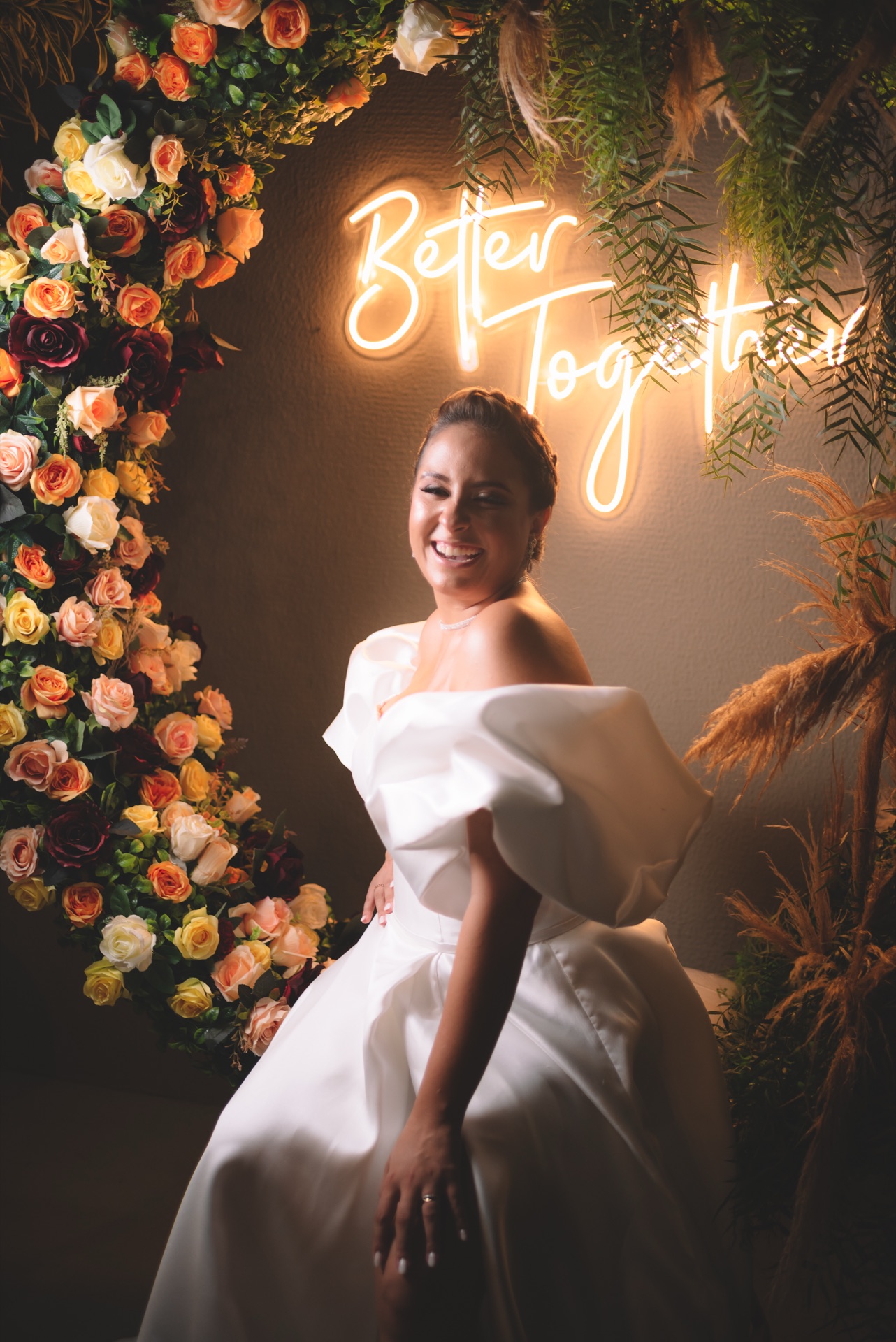 Noiva em frente a arco floral e letreiro neon Better Together