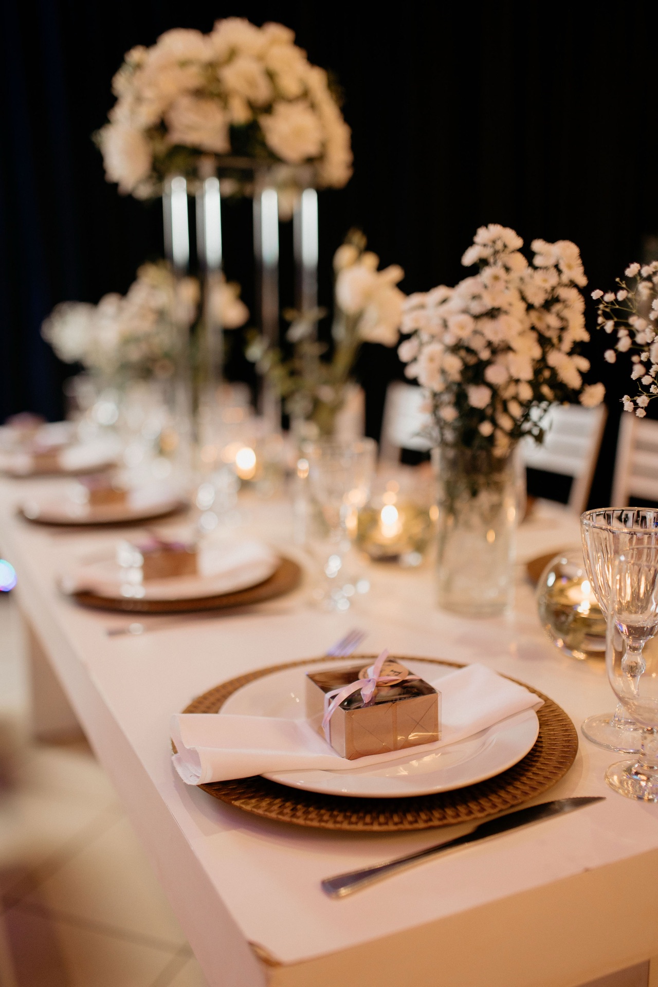 Mise en place com taças de cristal, sousplat dourado e centro de mesa floral